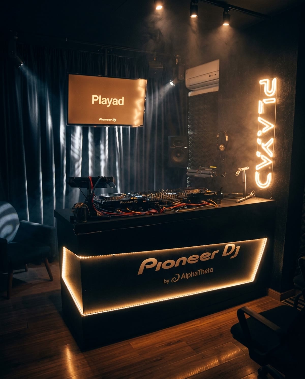 Cabine da PLAYAD com letreiro neon e balcão Pioneer DJ iluminado